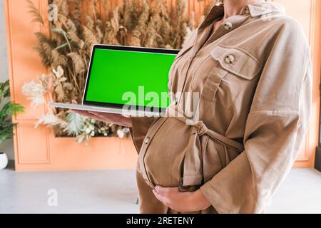 Un computer portatile con un'immagine a schermo verde su cui una ragazza incinta Foto Stock