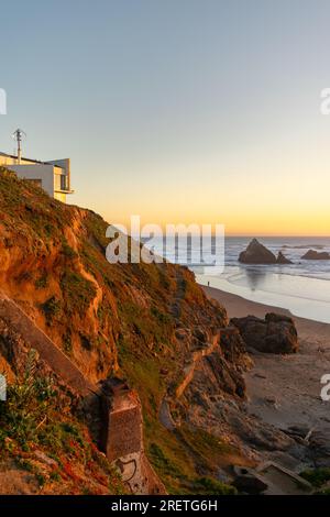 Casa sulla spiaggia sulla scogliera affacciata su un tranquillo tramonto del Pacifico. Foto Stock