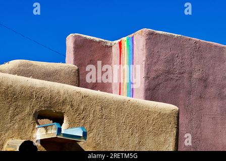 Taos, New Mexico, USA - 23 luglio 2023: Un tradizionale muro di adobe a Taos Plaza mostra una rappresentazione artistica di un arcobaleno, noto come "promessa di Dio". Foto Stock