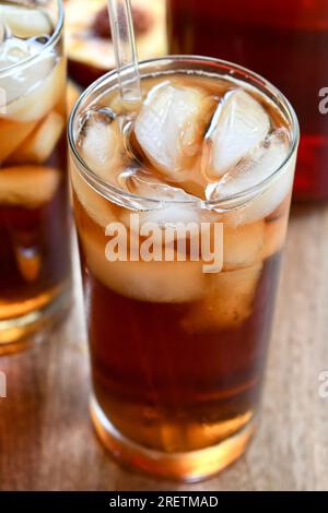 Due bicchieri di tè freddo aromatizzato alla pesca su una superficie di legno Foto Stock