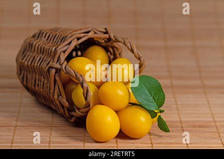 Prugne di ciliegio gialle, Prunus cerasifera, in cesto Foto Stock