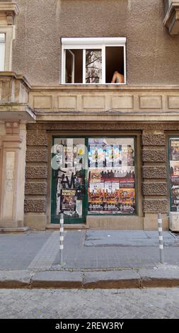 Edificio grigio con poster promozionali mentre un uomo tatuato si trova nella finestra. Sofia, Bulgaria. 29 luglio 2023 Foto Stock