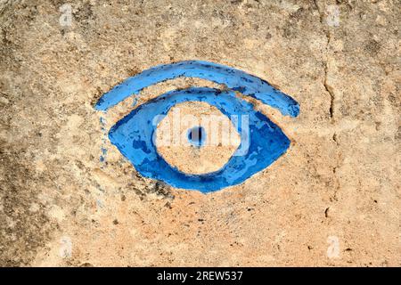 Primo piano dell'occhio blu dipinto sul muro presso la cava di arenaria, Lithica, Pedreres de S Hostal, Minorca, Isole Baleari Foto Stock
