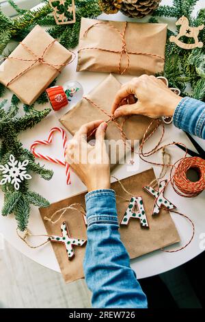 Donna che prepara regali di natale con corda e decorazioni di natale Foto Stock