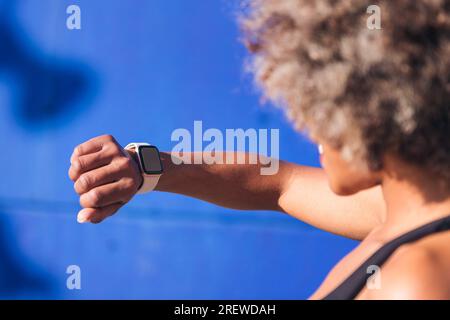 donna sportiva irriconoscibile che guarda l'orologio intelligente Foto Stock