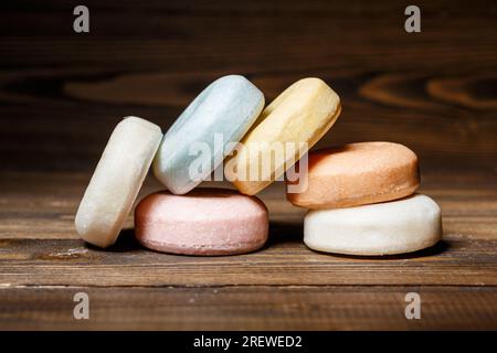 Barre colorate di shampoo rotondo asciutto su uno sfondo di legno. Cosmetici naturali, cura della pelle e concetto dermatologico Foto Stock