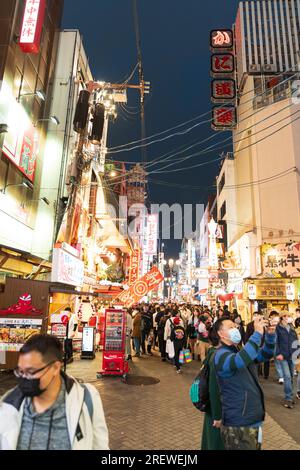 Folle di turisti che camminano per la famosa via Dotonbori di Osaka di notte sotto le luci accese e le indicazioni al neon per i numerosi ristoranti Foto Stock