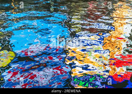 Riflesso notturno del famoso segno Glico dell'uomo che corre nel fiume Dotonbori, Osaka, che fornisce schemi casuali astratti nelle acque scure. Foto Stock