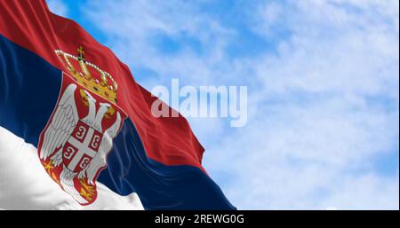 Bandiera nazionale della Serbia che sventola nel vento in una giornata limpida. Strisce rosse, blu e bianche con stemma in corrispondenza del paranco. rendering dell'illustrazione 3d. Flutterin Foto Stock