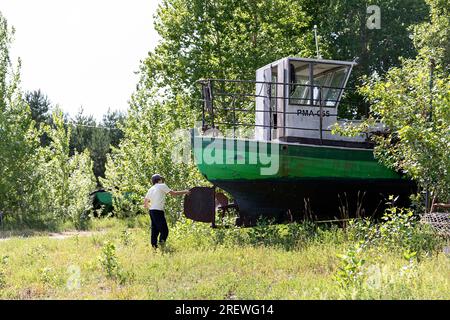 Ragazzo turista che esplora il vecchio peschereccio in legno abbandonato in una foresta sull'isola kihnu nel mar baltico, estonia Foto Stock