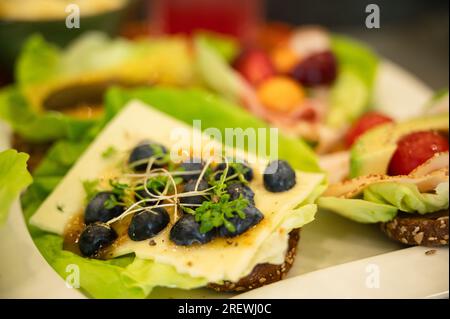 Panini sani e colorati con insalata, frutti di bosco, marmellata, formaggio e affettati Foto Stock