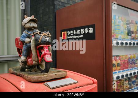 Giugno 2023, Tokoname City. Un postino in ceramica su una decorazione per moto sopra una cassetta postale accanto a un distributore automatico di bevande Foto Stock