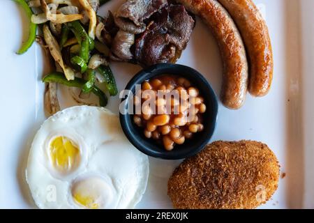 Colazione all'americana con uova, salsicce, pancetta, fagioli, patate con hash Brown e verdure saltate Foto Stock