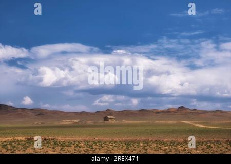 piccola casa solitaria in argilla nel deserto sotto un cielo nuvoloso Foto Stock