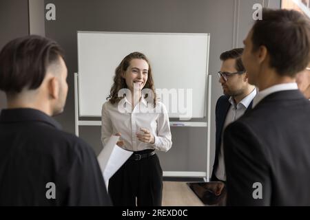 Felice e attraente giovane rappresentante aziendale che parla con i partner Foto Stock