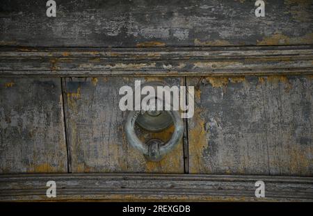 Antica porta in legno intemprata con battente in peltro d'epoca a Modica, Ragusa, Sicilia, Italia. Foto Stock