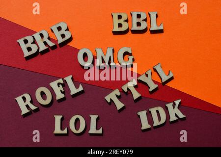 Acronimi utilizzati per i messaggi di testo, tra cui BRB, Be Right Back, ROFL, Rolling on Floor Laughing, TTYL, Talk to you later, in alfabeto di legno isolato Foto Stock