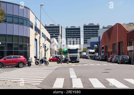 Barcellona, Spagna, 8 maggio 2023: Incrocio nella zona industriale della città vicino a magazzini, camion parcheggiati, auto in movimento lungo la strada Foto Stock