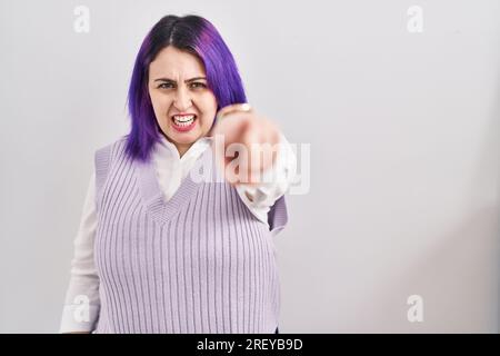 La donna più taglia ha i capelli viola che si erigono su sfondo bianco puntando dispiaciuto e frustrato alla macchina fotografica, arrabbiato e furioso con voi Foto Stock