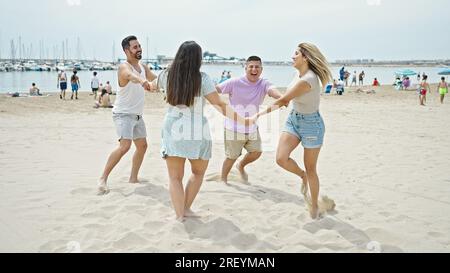Gruppo di persone sorridenti danzando fiduciosi con le mani insieme in spiaggia Foto Stock
