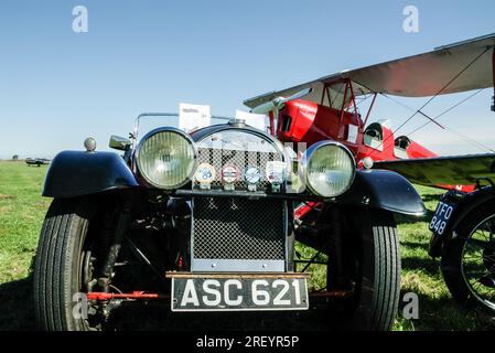 Aereo e auto d'epoca. Biplano Red Tiger Moth con il classico Morgan 4/4 del 1936, a Wings & Wheels Fly-in all'aerodromo di Turweston, Buckinghamshire, Regno Unito Foto Stock