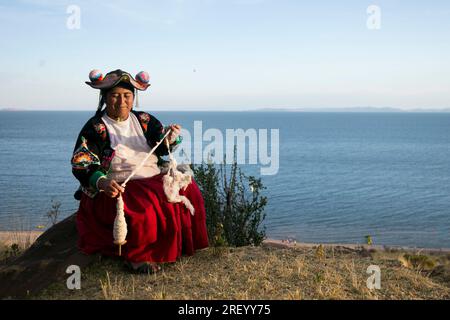 Llachon, Perù; 1 gennaio 2023: Una donna che lavora con la lana nella penisola di Llachon sul lago Titicaca. Foto Stock