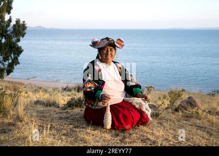 Llachon, Perù; 1 gennaio 2023: Una donna che lavora con la lana nella penisola di Llachon sul lago Titicaca. Foto Stock