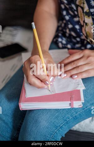 Una donna scrive una lista sulle commissioni giornaliere, la lista della spesa Foto Stock