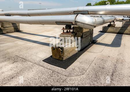 Tubi HVAC industriali isolati montati sul tetto su tetto grigi e supporti in legno. Foto Stock