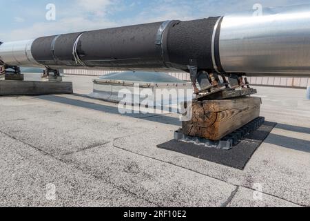 Tubi HVAC industriali isolati montati sul tetto su tetto grigi e supporti in legno. Foto Stock