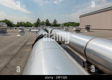 Tubi HVAC industriali isolati montati sul tetto su tetto grigi e supporti in legno. Foto Stock