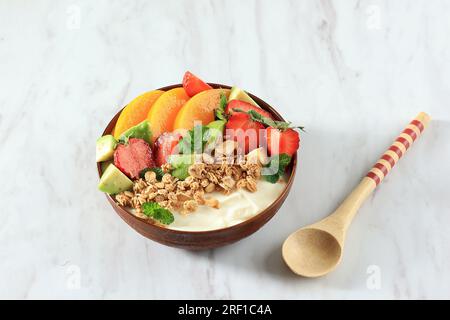 Fragole fresche e sane con yogurt e foglie di menta in ciotola su tavolo bianco, spazio copia Foto Stock