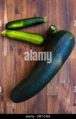 Zucchine grandi e piccole. Zucchine fresche su fondo di legno. Zucchine o zucchine biologiche su un tavolo di legno Foto Stock