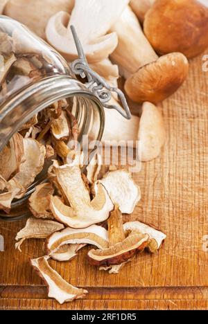 funghi in cesto su tavolo di legno. Pezzi tagliati di funghi in cesto, su fondo di legno, vicino a funghi freschi Foto Stock