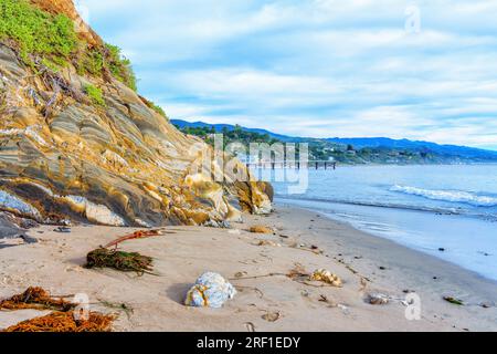 La maestosa costa di Malibu presenta un'enorme formazione rocciosa, una splendida spiaggia e un cielo panoramico con nuvole. Foto Stock