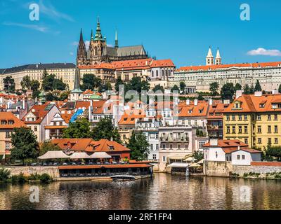 Case colorate con tetti rossi e St Cattedrale di Vito sullo sfondo sotto il cielo blu a Praga, Repubblica Ceca. Foto Stock