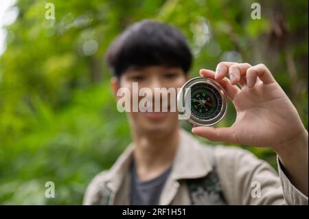 Immagine a fuoco selettiva, Un felice escursionista asiatico con una bussola, Un'escursione o un'esplorazione della foresta da solo. Foto Stock