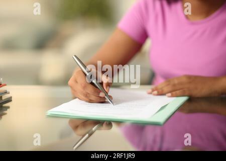 Ritratto ravvicinato di una donna nera che compila il modulo su una scrivania a casa Foto Stock