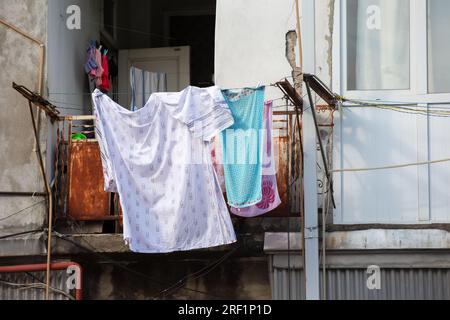 La lavanderia è appesa per asciugarsi su un vecchio balcone malandato. Foto Stock