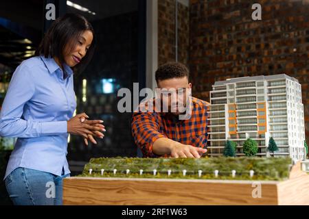 Diversi architetti maschi e femmine discutono e lavorano su un modello di edificio in ufficio Foto Stock