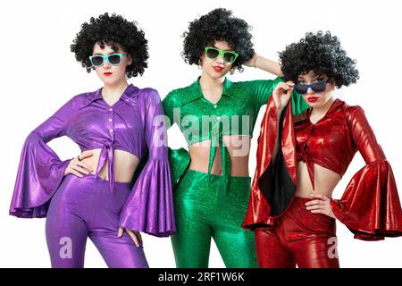 Un gruppo di ragazze da discoteca con parrucche afroamericane e costumi colorati su sfondo bianco. La moda degli anni Settanta e Ottanta. Foto Stock