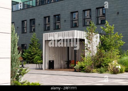 Moderna zona fumatori all'esterno. business building, gazebo in legno con sedie. Zona verde. Moderno business center Foto Stock