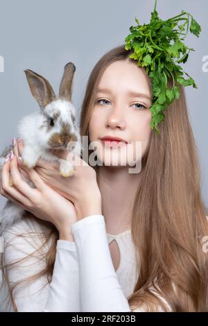 Ritratto di una ragazza rurale con un mucchio di prezzemolo sulla testa e un coniglio. Foto Stock