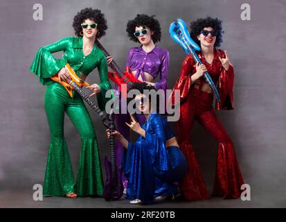 Gruppo di ragazze in stile discoteca con chitarre giocattolo. Gruppo disco vintage per donne. Foto Stock