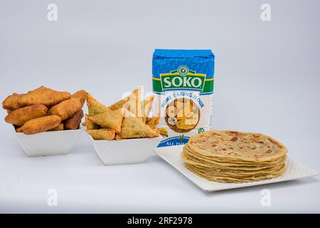 Chapati Mandazi Andazi Samosa spuntini triangolari su un piatto su sfondo bianco nella città di Nairobi, nella contea del Kenya, nell'Africa orientale. Cibo delizioso Foto Stock