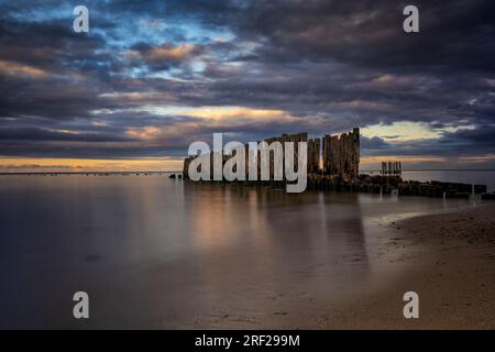 Il vecchio molo rimane sul Mar Baltico, pali di legno in acqua liscia al crepuscolo a Babie Doly, Gdynia, Polonia. Foto Stock