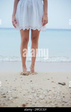 Gambe femminili in piedi sulla sabbia della spiaggia Foto Stock