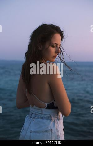 Ritratto ravvicinato di una giovane donna in piedi sulla riva del mare Foto Stock