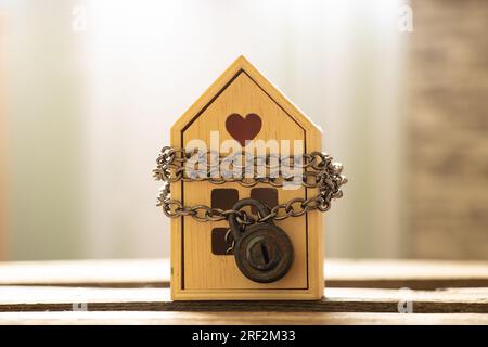 La casa è incatenata e chiusa a lucchetto e si erge su una tavola di legno, il concetto di divieto di vendita di immobili, protezione della casa Foto Stock