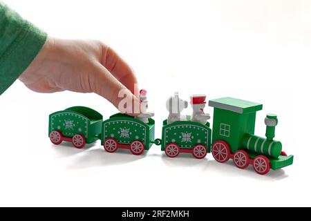 Un bambino sta giocando con un treno di Natale. Sfondo bianco. Primo piano. Elemento per creare l'atmosfera natalizia Foto Stock